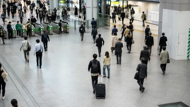 Crowded passenger concourse and JR transfer gates at Shinjuku Station.